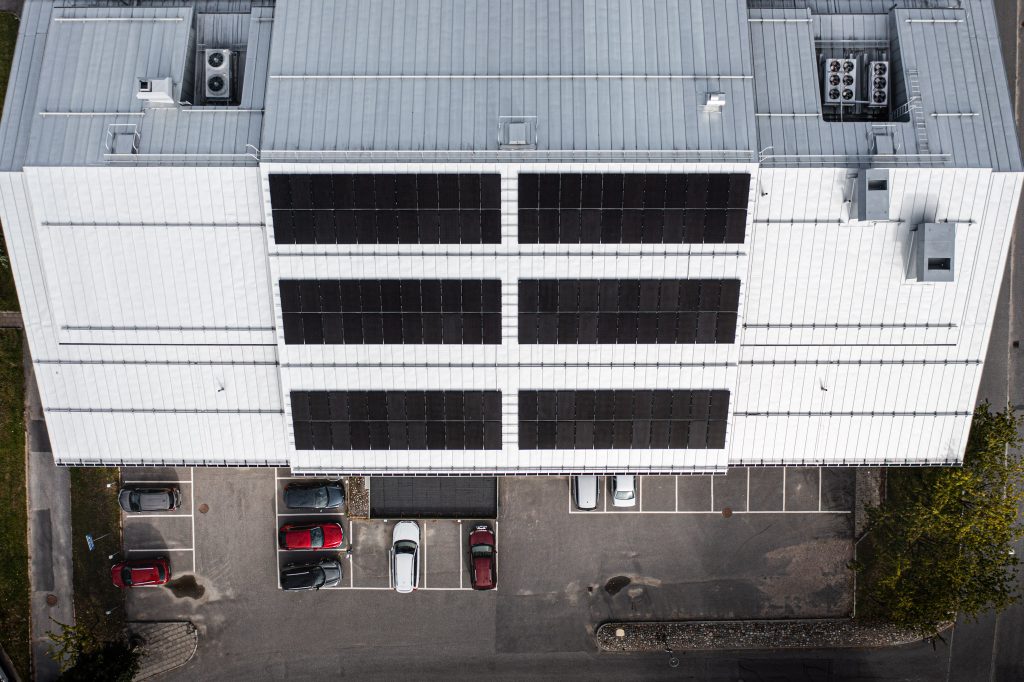 Bild på solcellspaneler installerade på ett tak. Panelerna är mörka och rektangulära, ordnade i rader som täcker en stor del av taket.