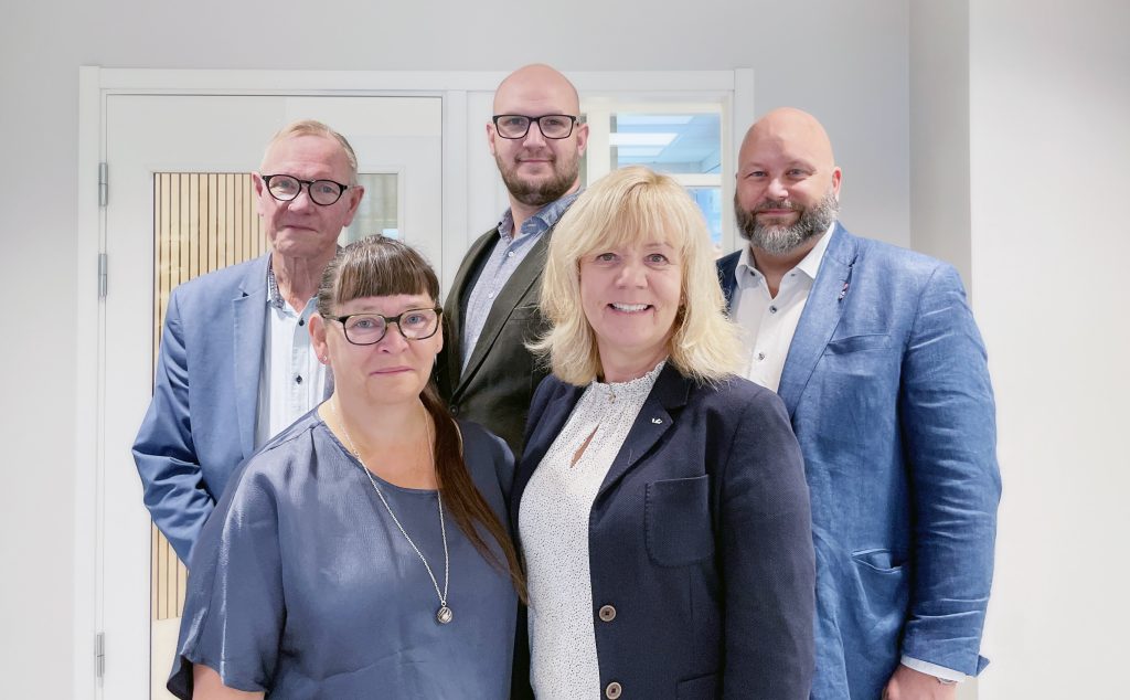 Bilden visar fem personer, styrelsen för Piteå Näringsfastigheter AB, som står uppställda mot en vägg. Alla tittar in i kameran med ett vänligt uttryck.