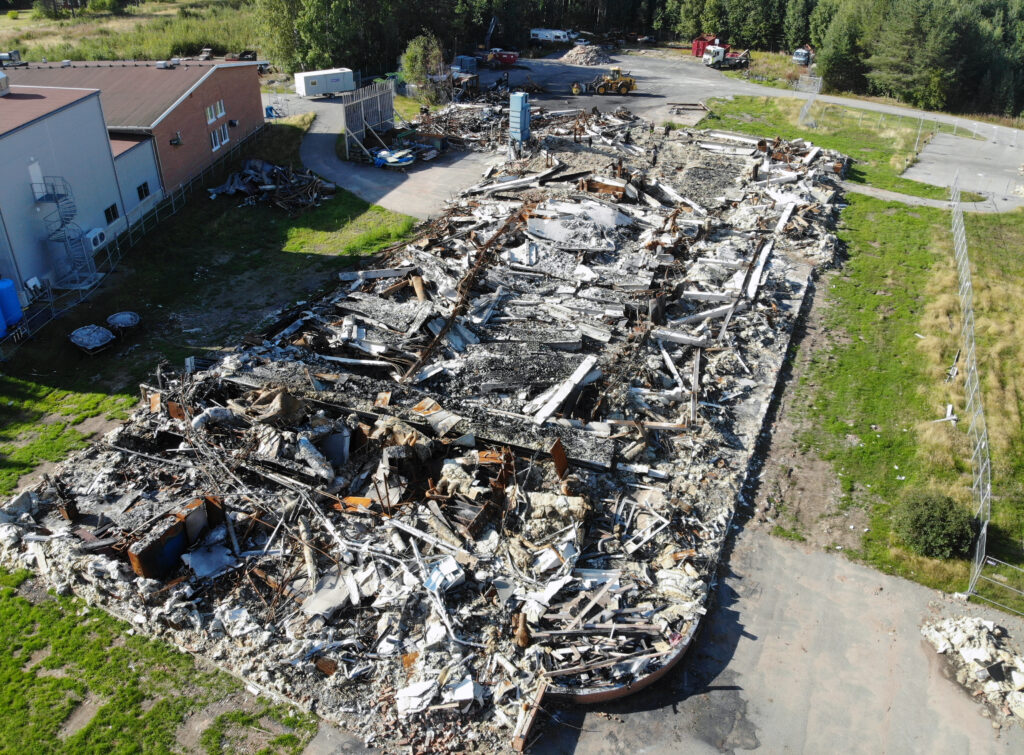Drönarbild rakt ovanifrån visar brandresterna efter en fastighet.