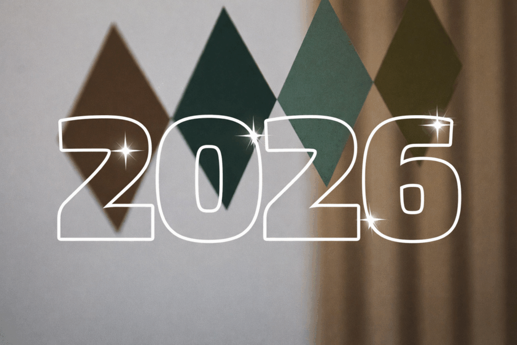 Stora vita siffror 2026 med glittrande stjärnor framför en mjuk bakgrund av färgade romber i grönt och brunt samt en beige gardin.