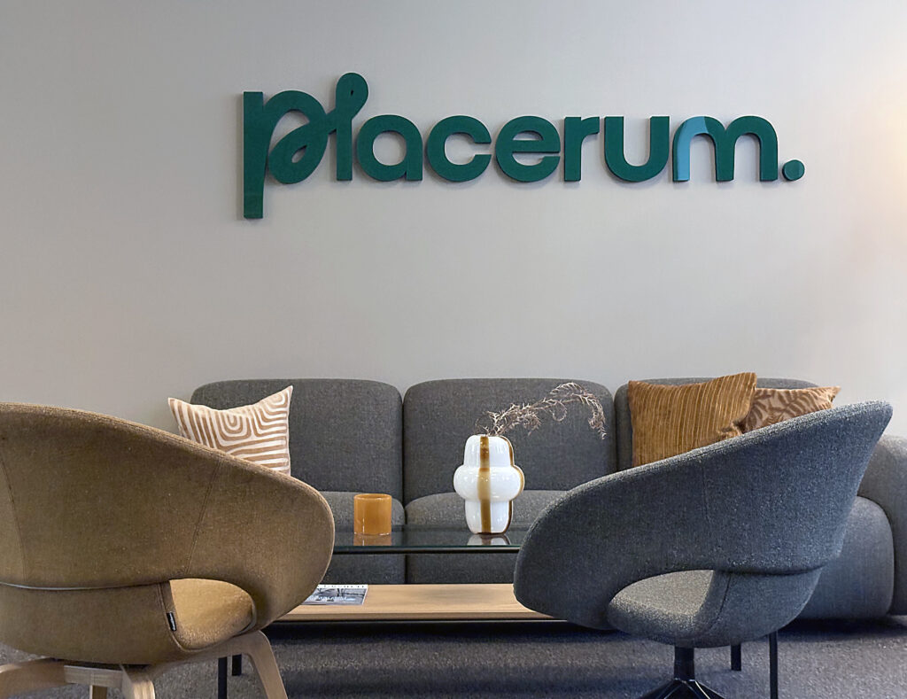 Närbild av sittgrupp med grå soffa och två fåtöljer. På väggen ovanför sitter den gröna logotypen placerum.